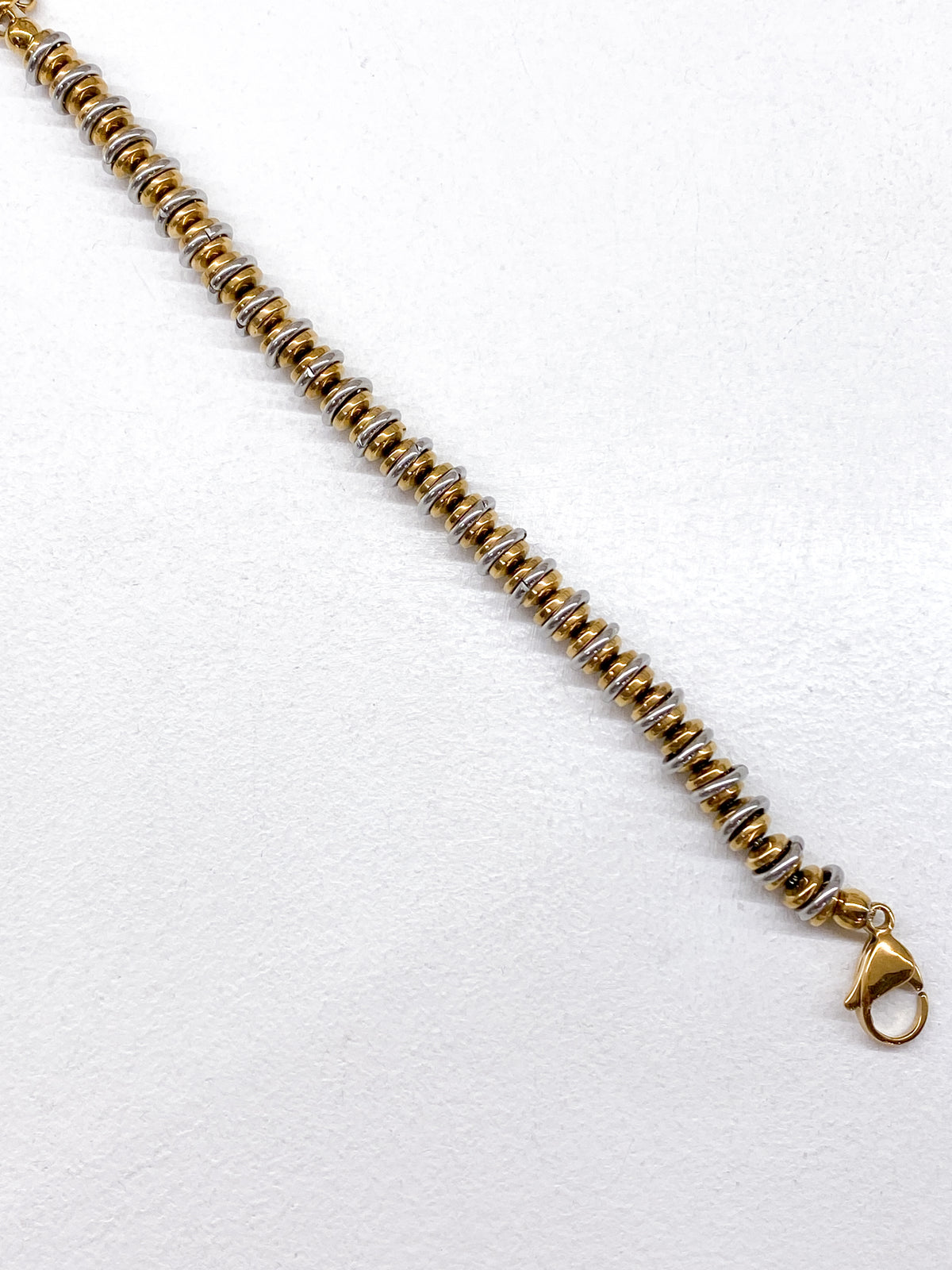 Bracelet en acier inoxydable avec rondelles dorées et anneaux argentés