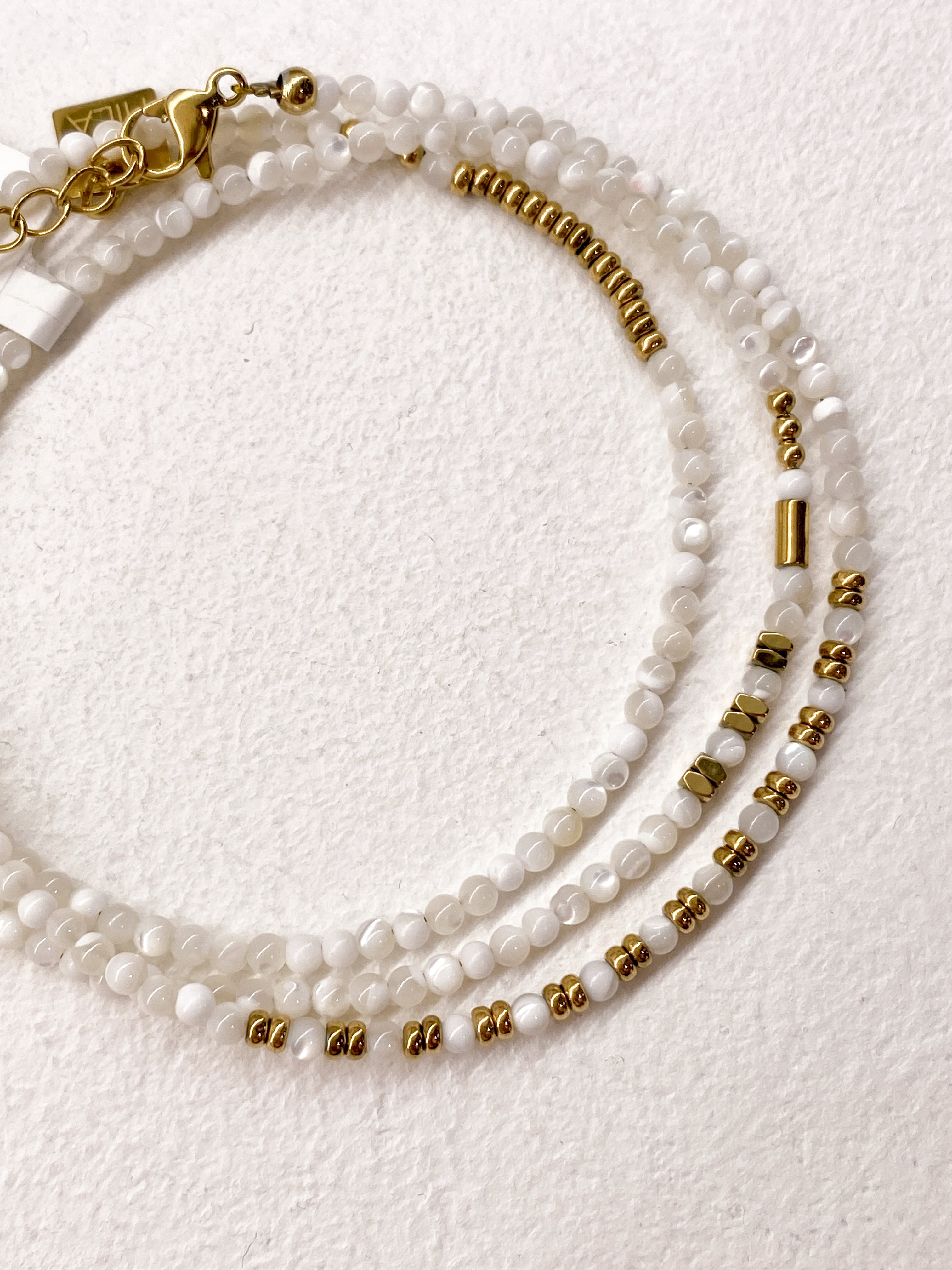 Bracelet blanc multi-rangs avec éléments géométriques