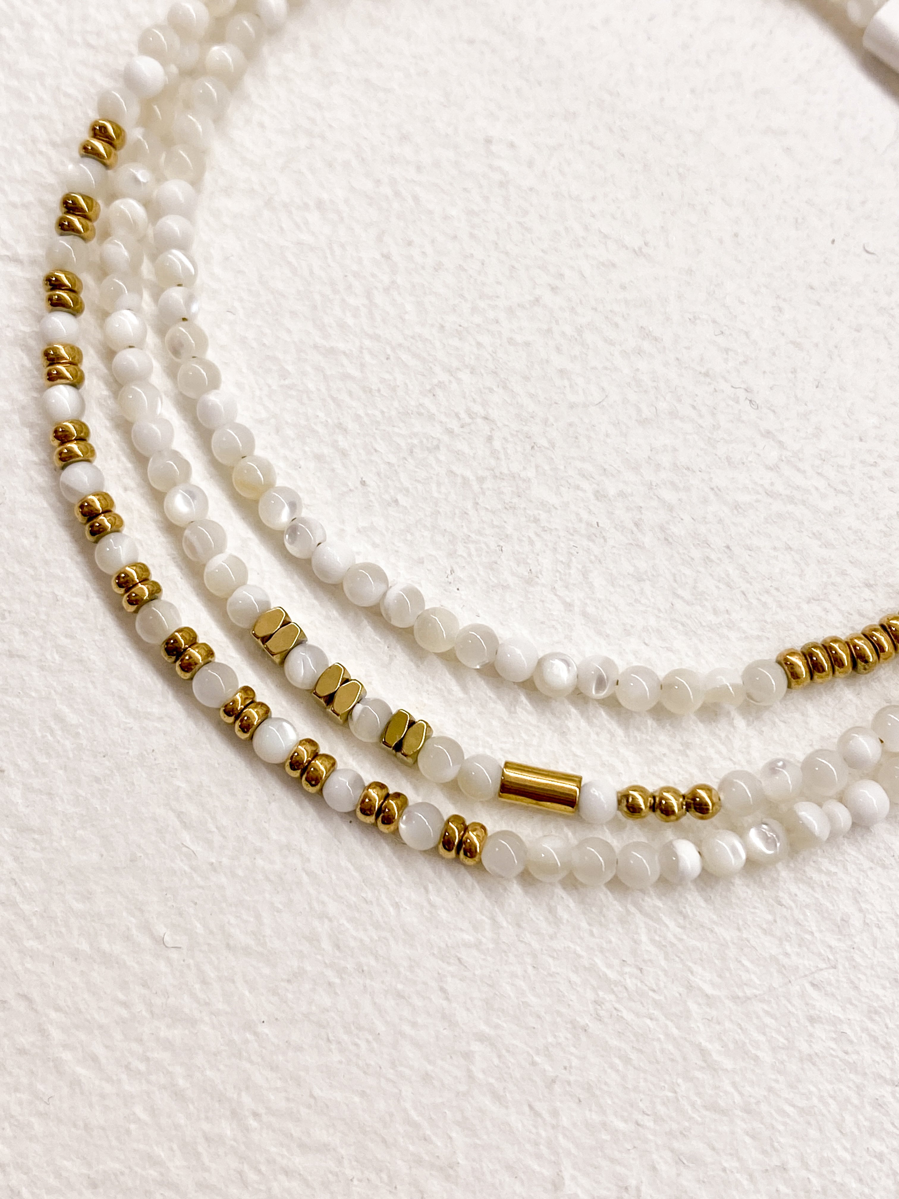 Bracelet blanc multi-rangs avec éléments géométriques