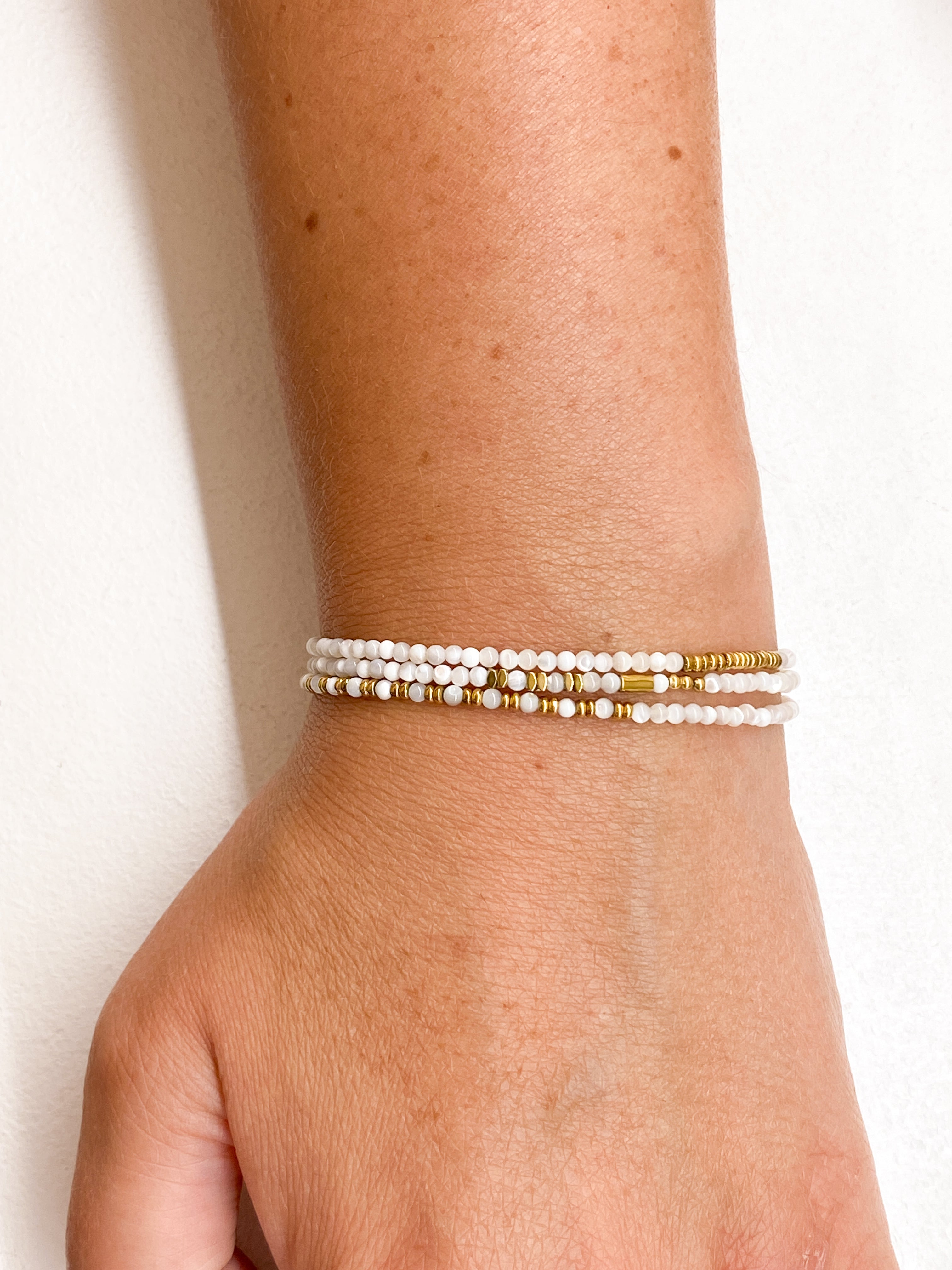 Bracelet blanc multi-rangs avec éléments géométriques