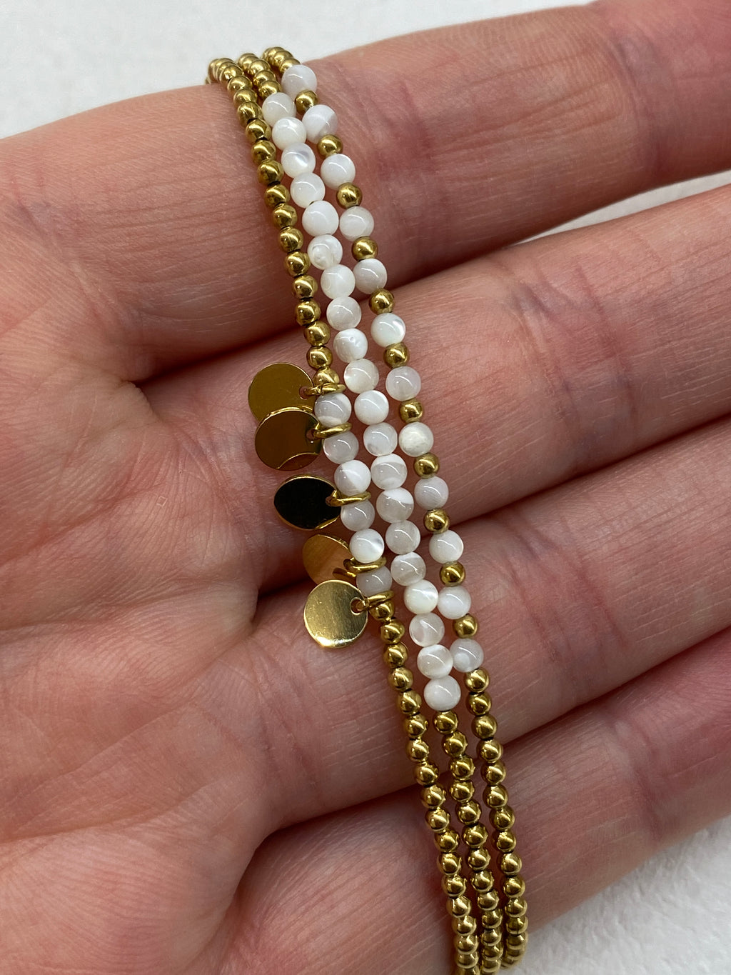 Bracelet multi-rangs blanc avec médaillons dorés