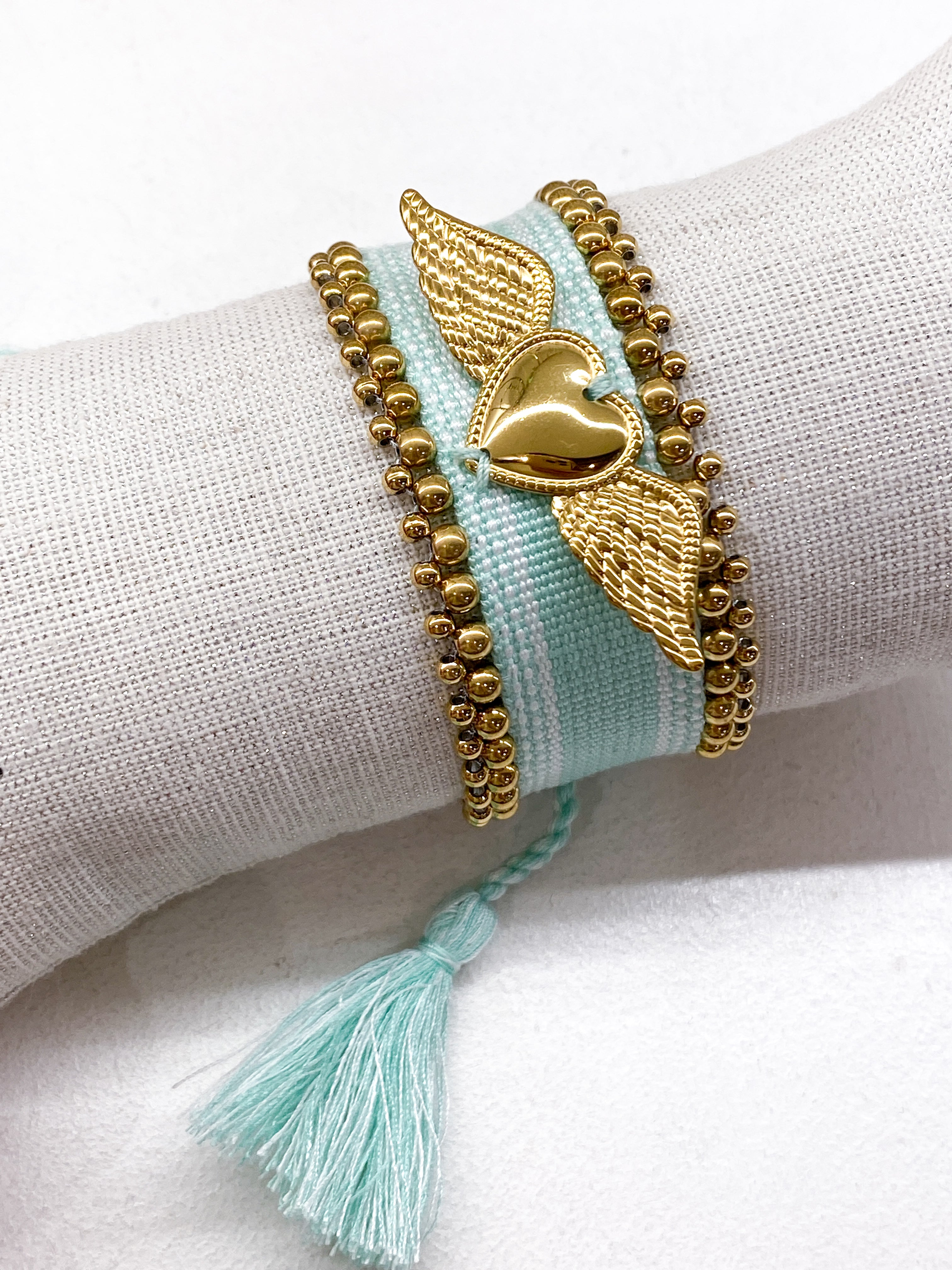 Bracelet large tissé coulissant avec perles dorées et cœur ailé