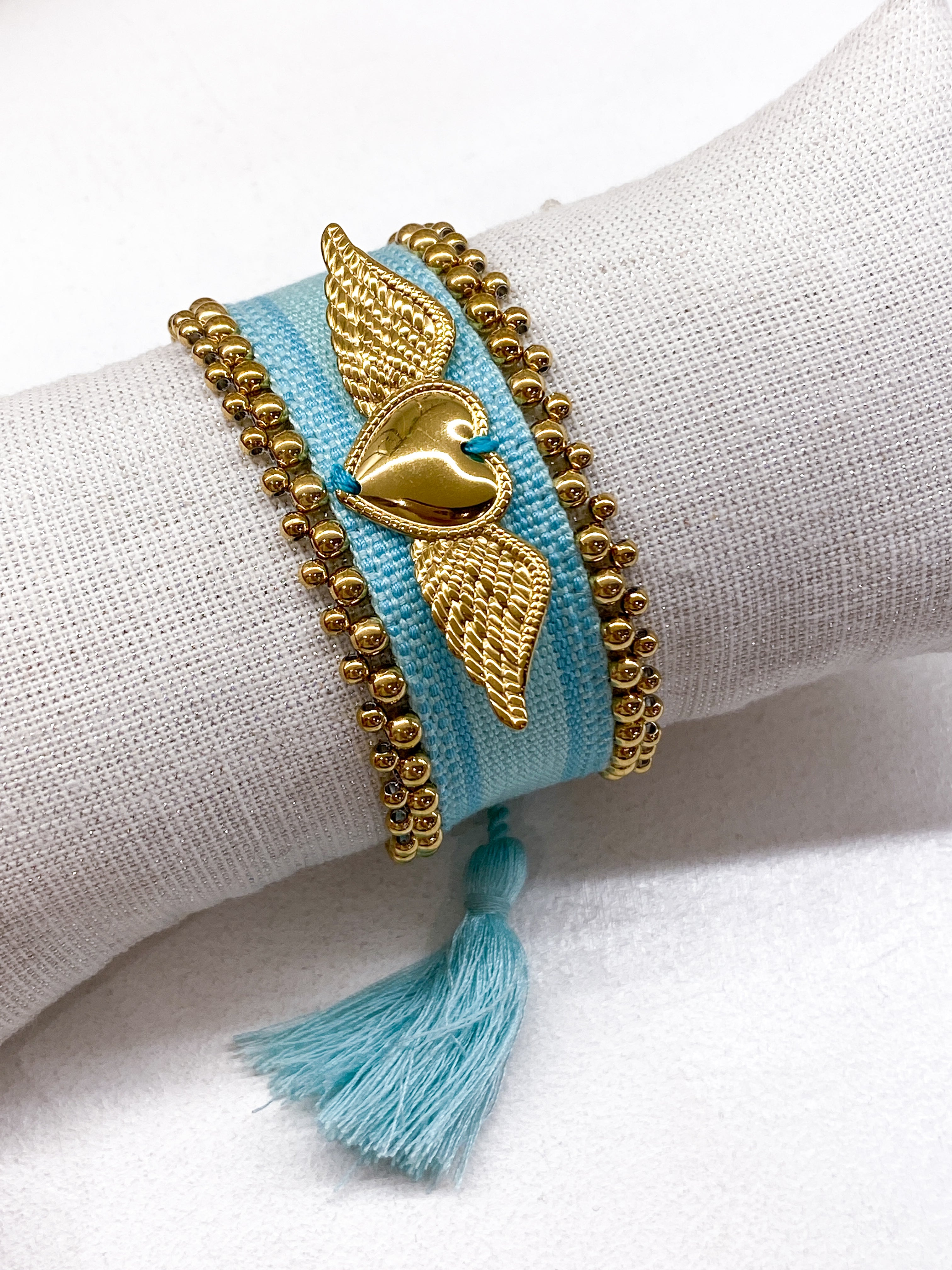 Bracelet large tissé coulissant avec perles dorées et cœur ailé